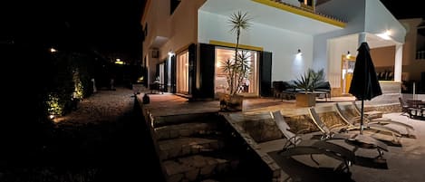A two-story house with a patio area, outdoor seating, and potted plants.