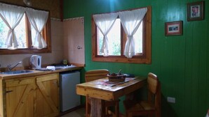 A kitchen with a wooden table and chairs, a sink, and a small refrigerator. - Tierras del Sur I (Villa La Angostura)