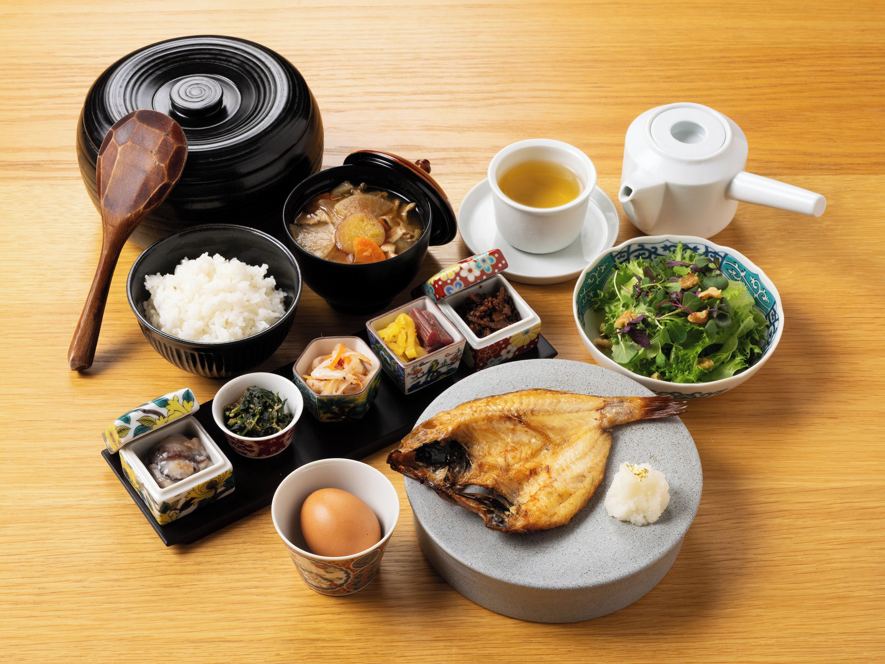 Eine traditionelle japanische Mahlzeit mit Reis, Suppe, Fisch und Tee auf einem Holztisch.