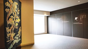 A room with a large black tapestry with gold embroidery, a window, and a wall with text and a small icon.