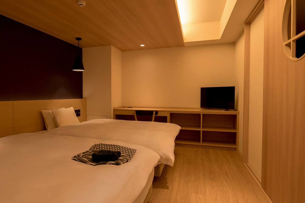 Habitación de hotel con dos camas, televisión y escritorio.