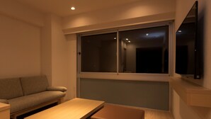 A modern living room with a sofa, a coffee table, and a TV mounted on the wall.