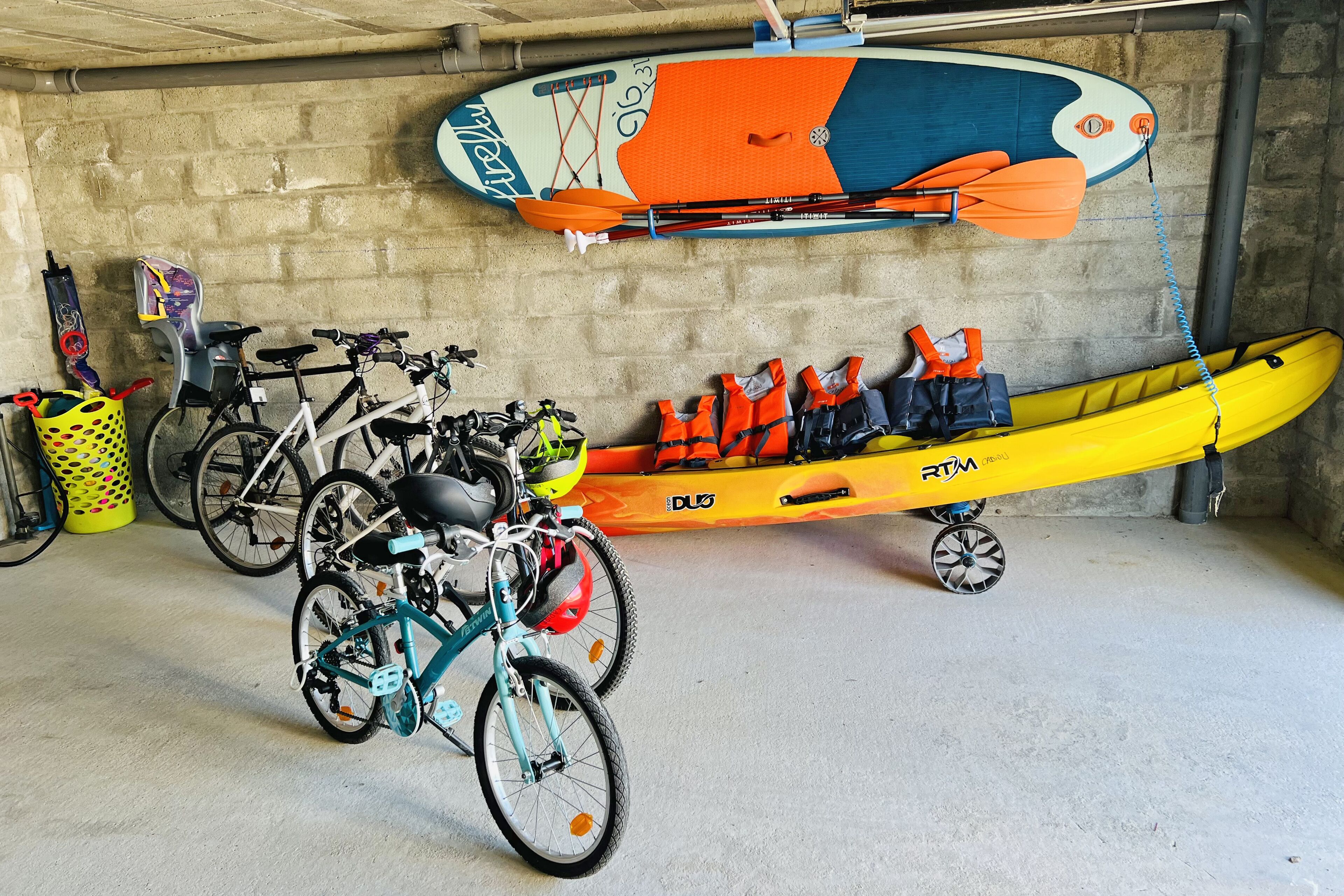 Un garaje con bicicletas, kayaks y chalecos salvavidas.