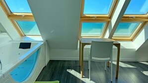 A room with skylights, a bathtub, a table, and a chair. - Beachfront villa, spectacular sea view, electric charging station (Plouescat)