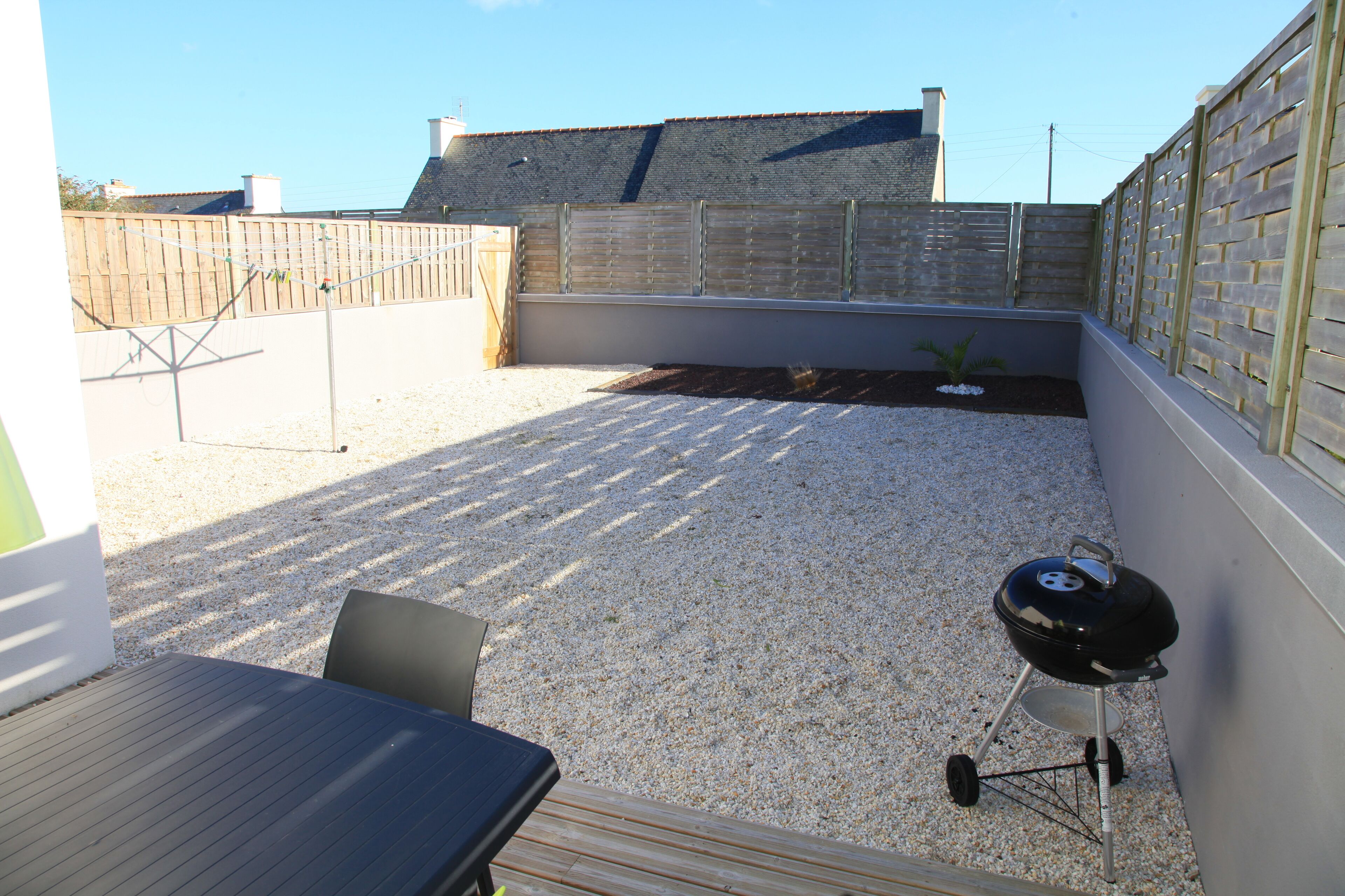 Un jardin avec un barbecue, une table et des chaises.