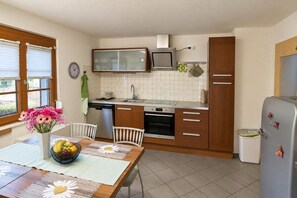 A kitchen with a dining table, chairs, a refrigerator, a microwave, and a sink. - Cozy **** - star apartment with large covered balcony (Schuttertal)