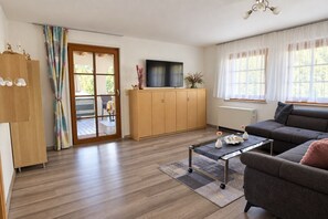 Un salon moderne avec un canapé, une table basse et un téléviseur posé sur un meuble en bois.