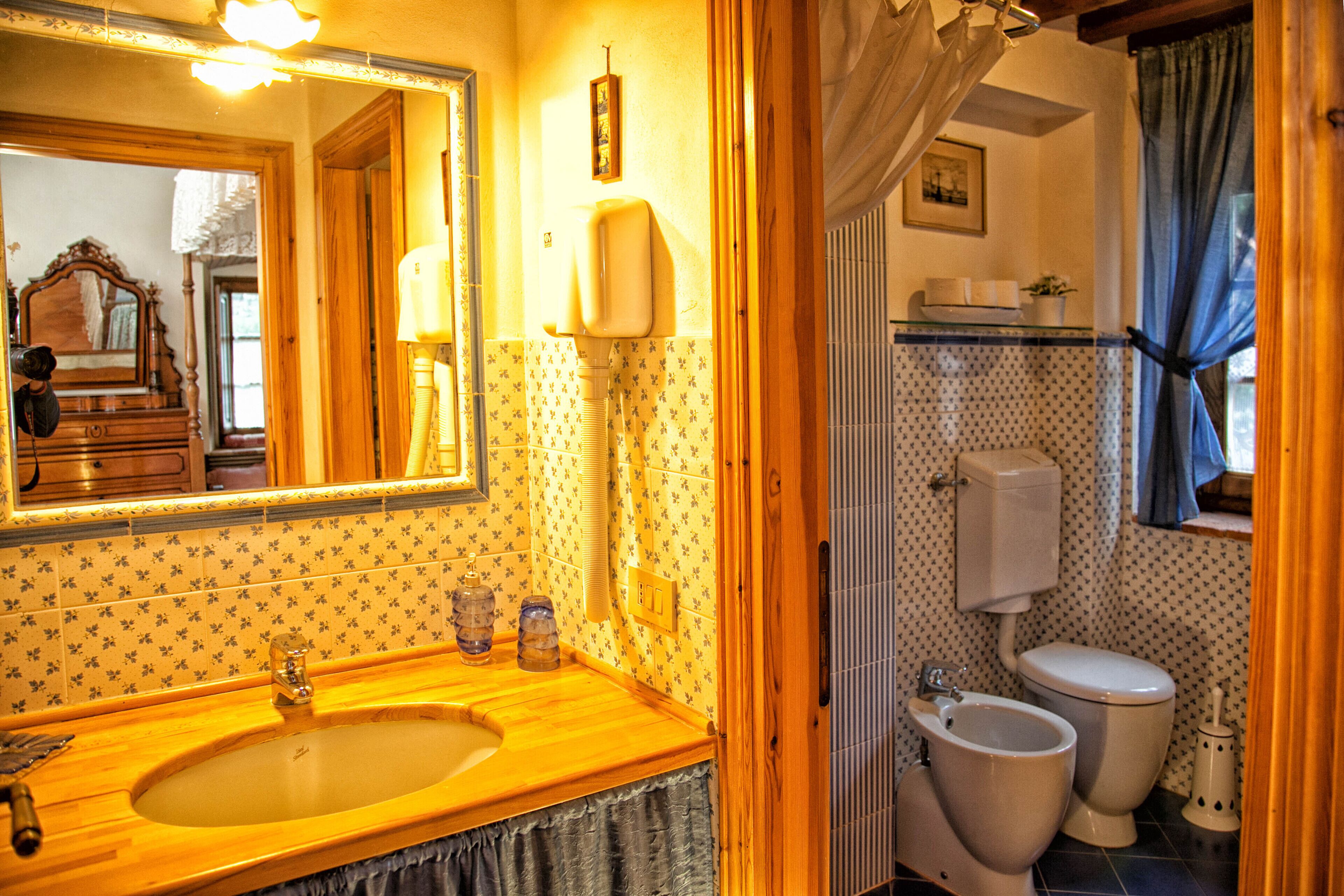 A bathroom with a wooden vanity, a sink, a mirror, a toilet, and a shower curtain.