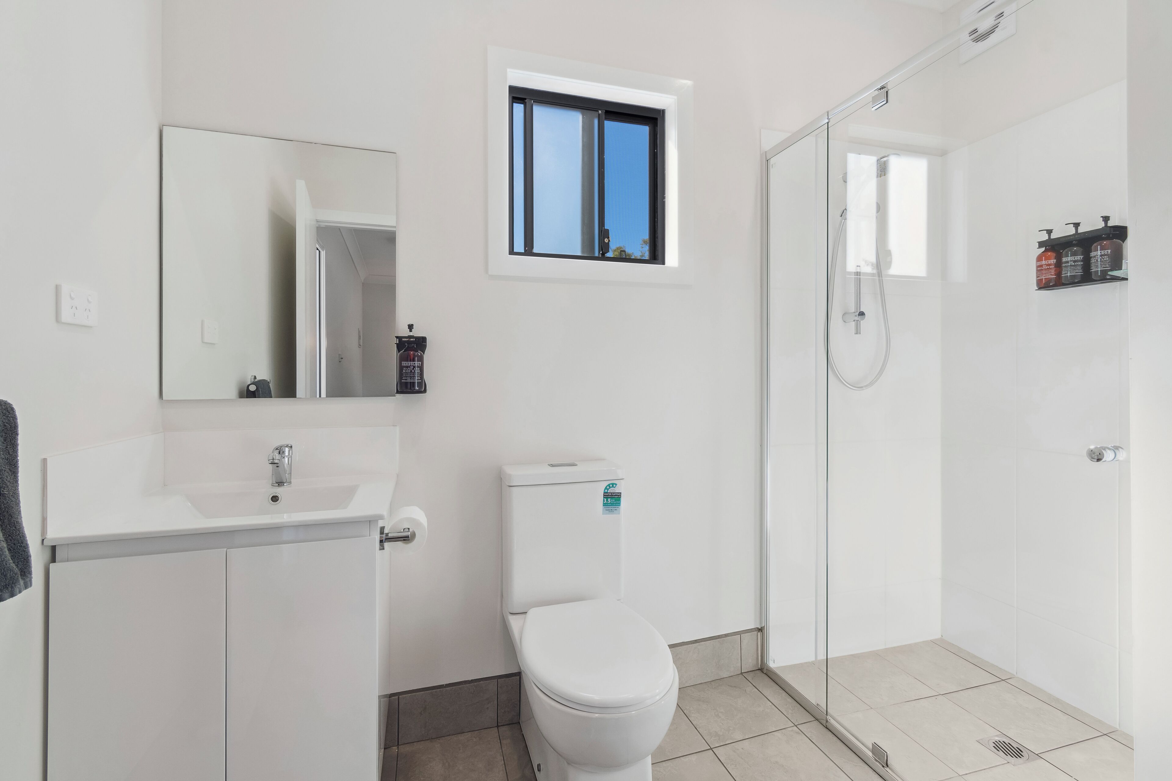 Een moderne badkamer met toilet, wastafel en douchehoek.