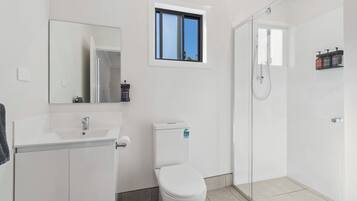 Een moderne badkamer met toilet, wastafel en douchehoek.