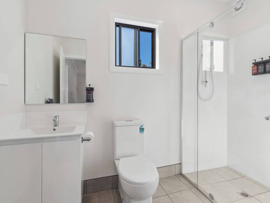 Een moderne badkamer met toilet, wastafel en douchehoek.