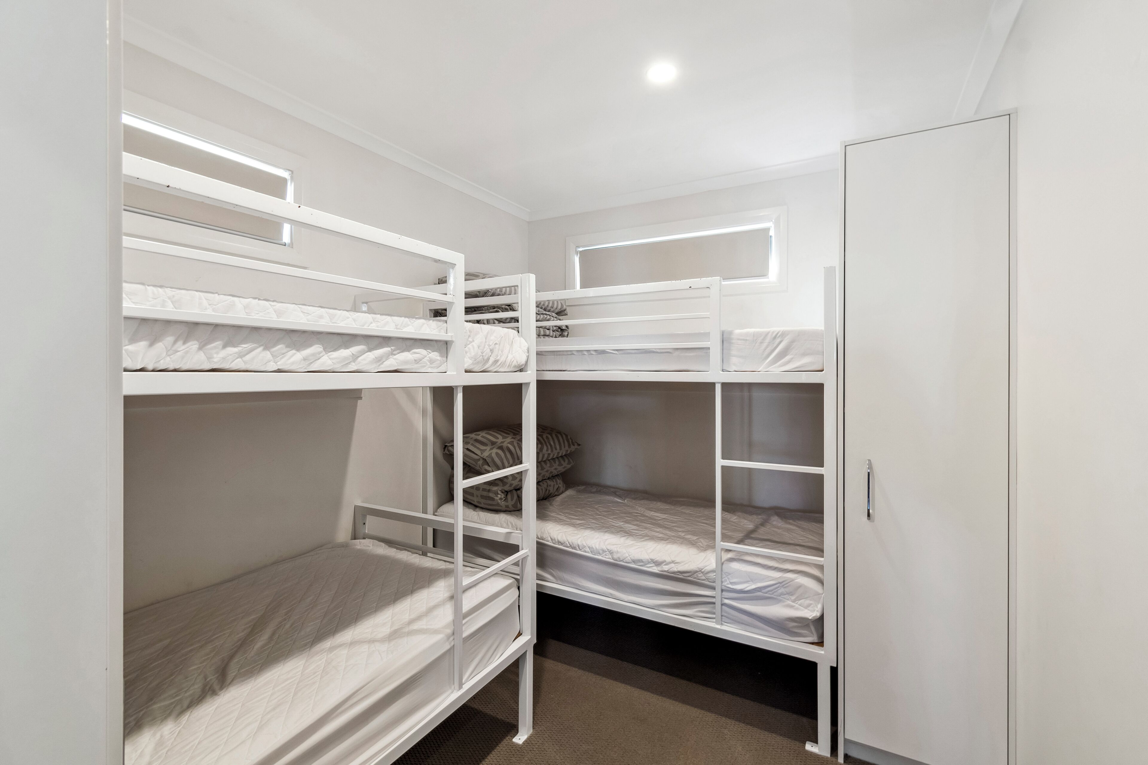 Dormitorio con literas, un armario y una ventana.