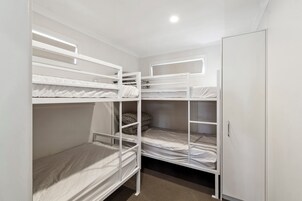 Dormitorio con literas, un armario y una ventana.