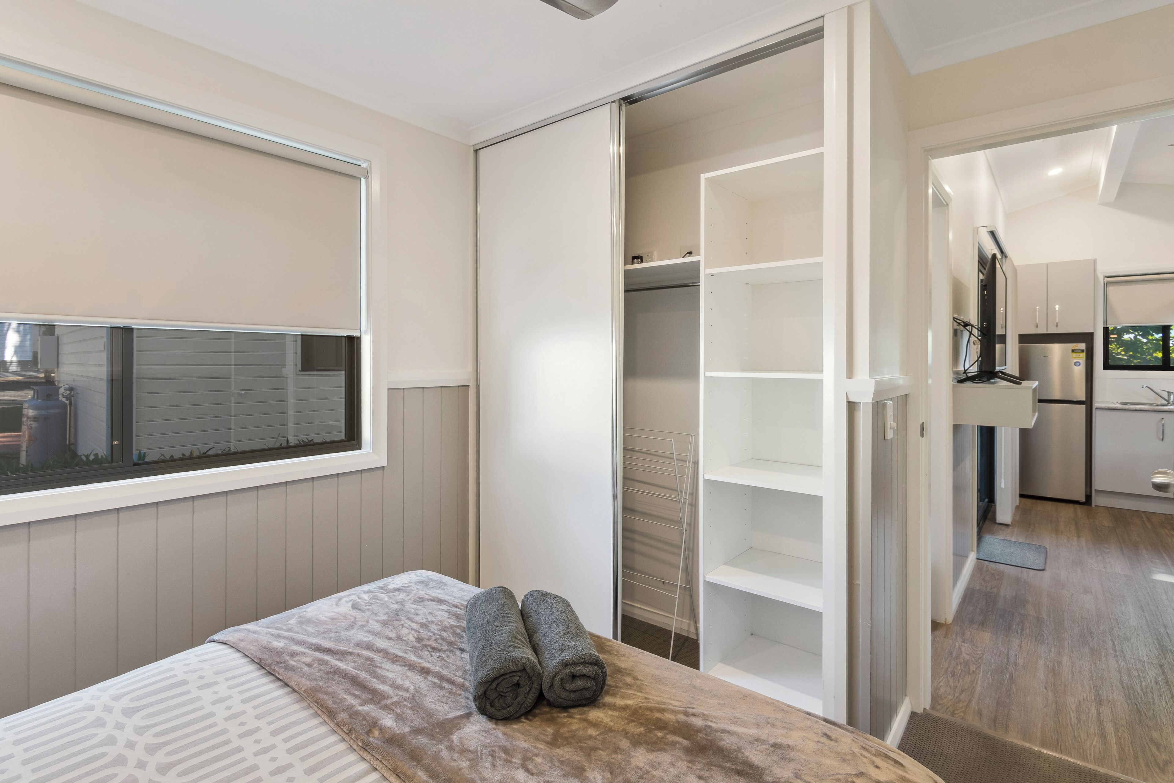 Une chambre à coucher avec un lit, une fenêtre, un placard et une vue sur la cuisine.