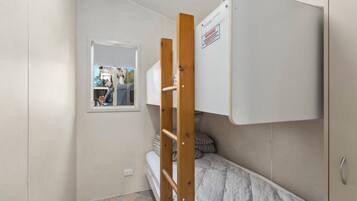 Una stanza piccola e compatta con un letto a castello, una scala in legno, una finestra e una porta.