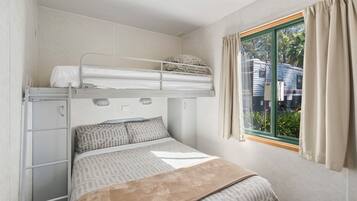 Quarto com beliche, janela, cortinas e vista para uma casa lá fora.