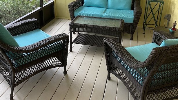 A covered patio with wicker furniture and a view of the outdoors.