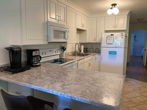 A kitchen with white cabinets, a microwave, a refrigerator, a stove, and a coffee maker.