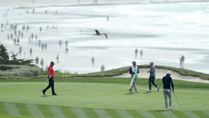 Un campo de golf con un obstáculo acuático y espectadores.