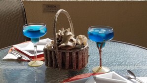 A table set for two with a tropical view, including a beach and palm trees. - Escape to the Caribbean! Beachfront Condo Starting at Just $145/Night! (Christiansted)