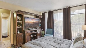 Camera d'albergo con un letto grande, una televisione su un mobile in legno, una poltrona e vista sull'esterno dalla finestra.