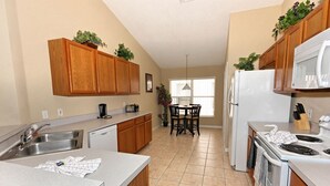 A kitchen with wooden cabinets, a dishwasher, a refrigerator, and a dining table with chairs.