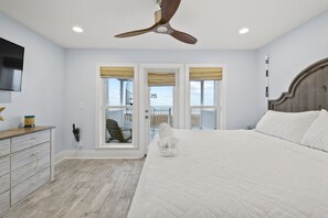 Un dormitorio con una cama grande, ventilador de techo y vistas al exterior a través de una puerta.