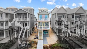 Un complejo residencial frente a la playa con varias casas de dos plantas, cada una con balcones y una entrada central con un paseo cubierto.