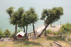 A lakeside area with trees, a wooden bench, and a red structure.