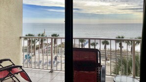 A balcony with a view of the sea, a chair, a table, and a railing. - 4th Floor on the beach! RIGHT ABOVE THE POOL. Tootsie’s right next door!!!! (Panama city beach)
