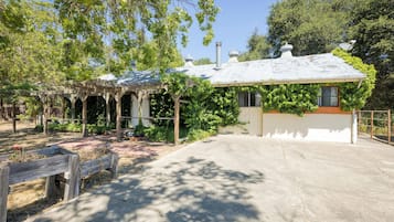 Traditional building surrounded by lush greenery and a shaded pergola.