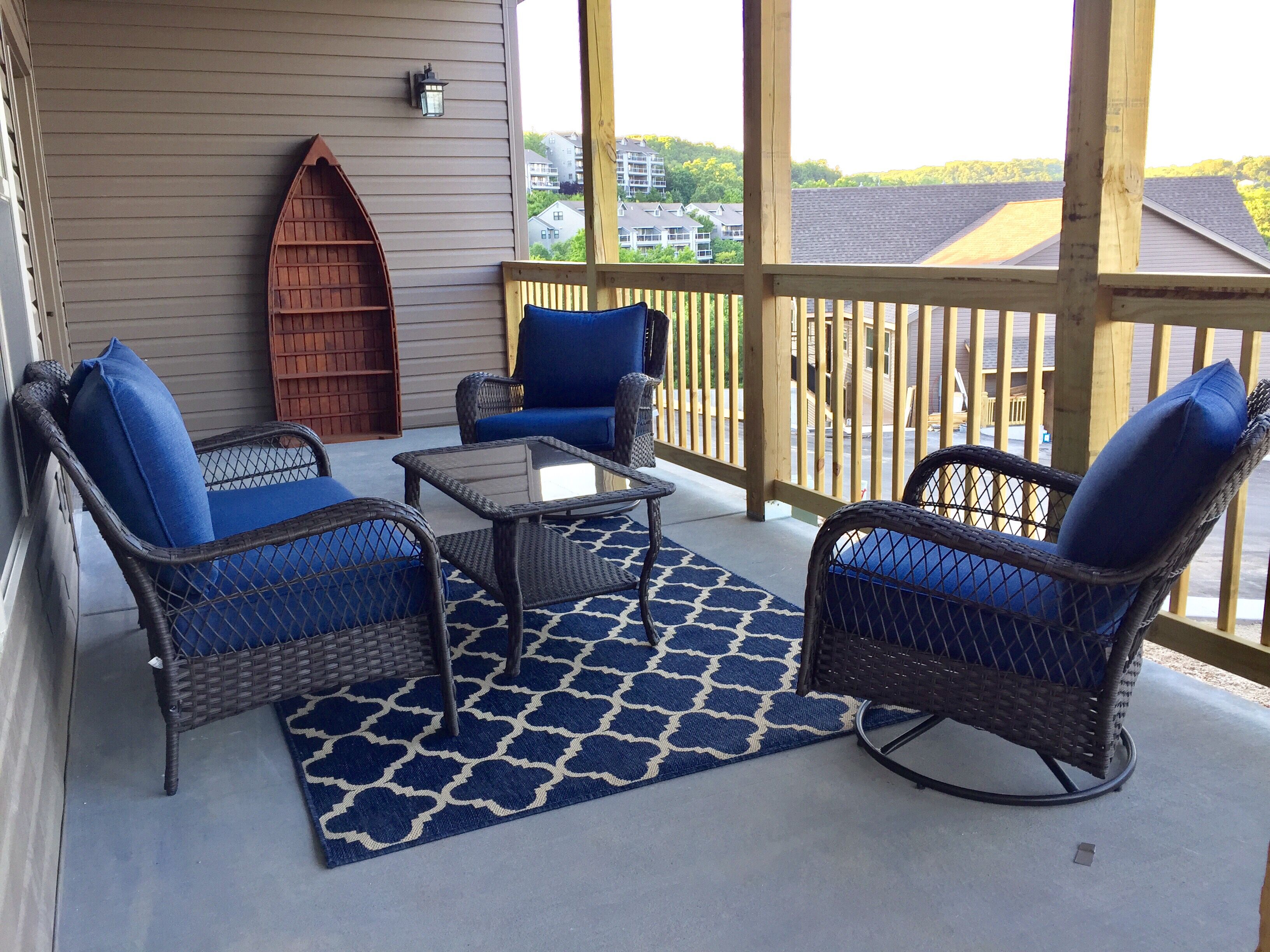 A covered outdoor seating area with wicker furniture and a patterned rug.