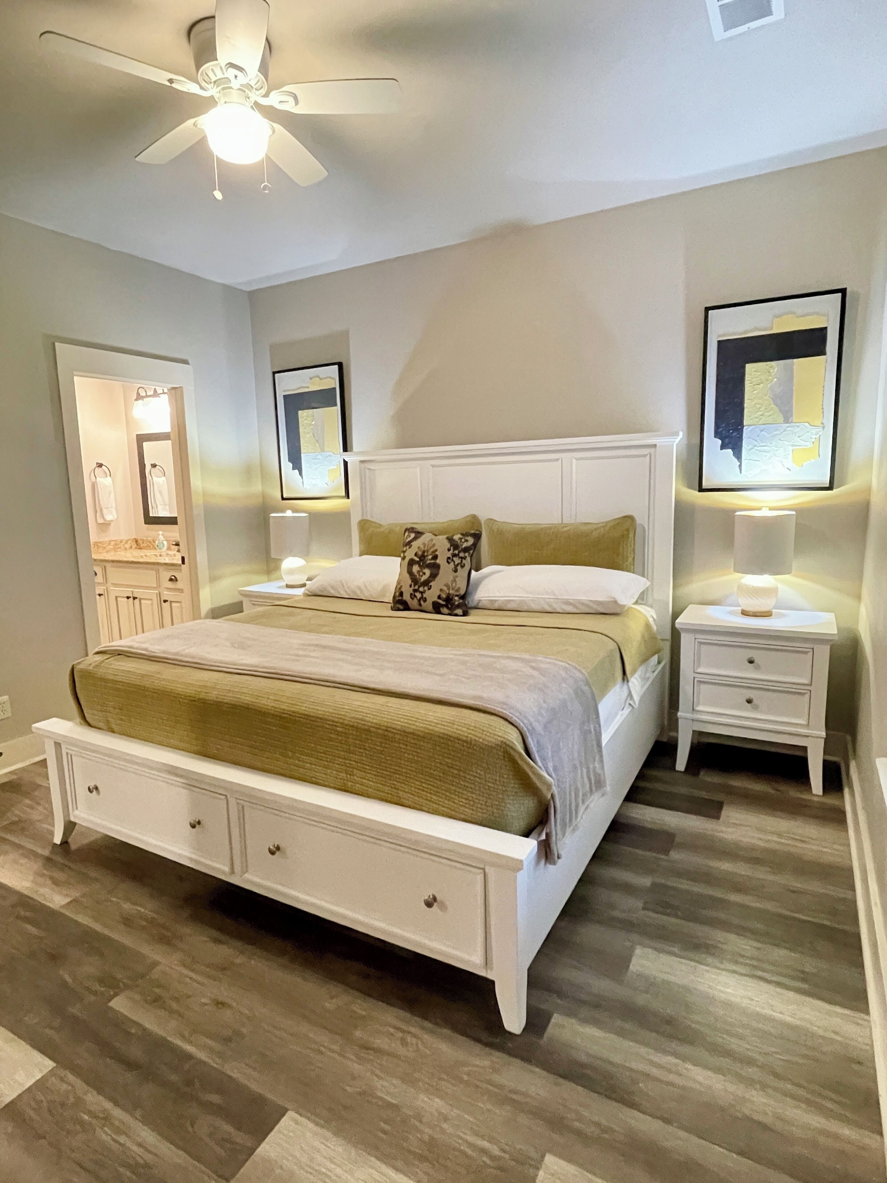 A bedroom with a bed, bedside tables, a ceiling fan, and a nightstand with a lamp.