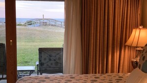 Ein Schlafzimmer mit Bett, Stuhl und Blick auf Strand und Steg.