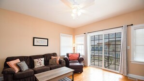 A living room with a brown sofa, a wooden coffee table, a red armchair, and a view through large windows to the outside. - WOW! LOW LOW RATES WINTER+SPRING!!!  Pets Ok-NO PET FEE! (Brigantine)