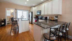 A kitchen with white cabinets, a granite countertop, and a central island with bar stools. - WOW! LOW LOW RATES WINTER+SPRING!!!  Pets Ok-NO PET FEE! (Brigantine)