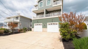 A two-story residential building with a balcony, two garage doors, and a driveway. - WOW! LOW LOW RATES WINTER+SPRING!!!  Pets Ok-NO PET FEE! (Brigantine)