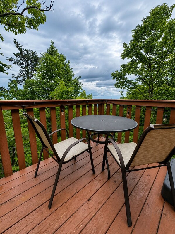 Eine Holzterrasse mit einem runden Tisch und zwei Stühlen, umgeben von einer Holzbrüstung.