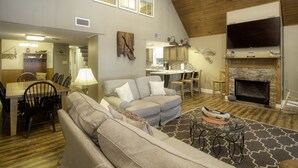 A spacious living room with a high ceiling, a fireplace, a dining area with a table and chairs, and a cozy seating area with a sofa and a patterned rug. - Y-Knott Lodge! Relax on the shores of Toledo Bend! (Many)