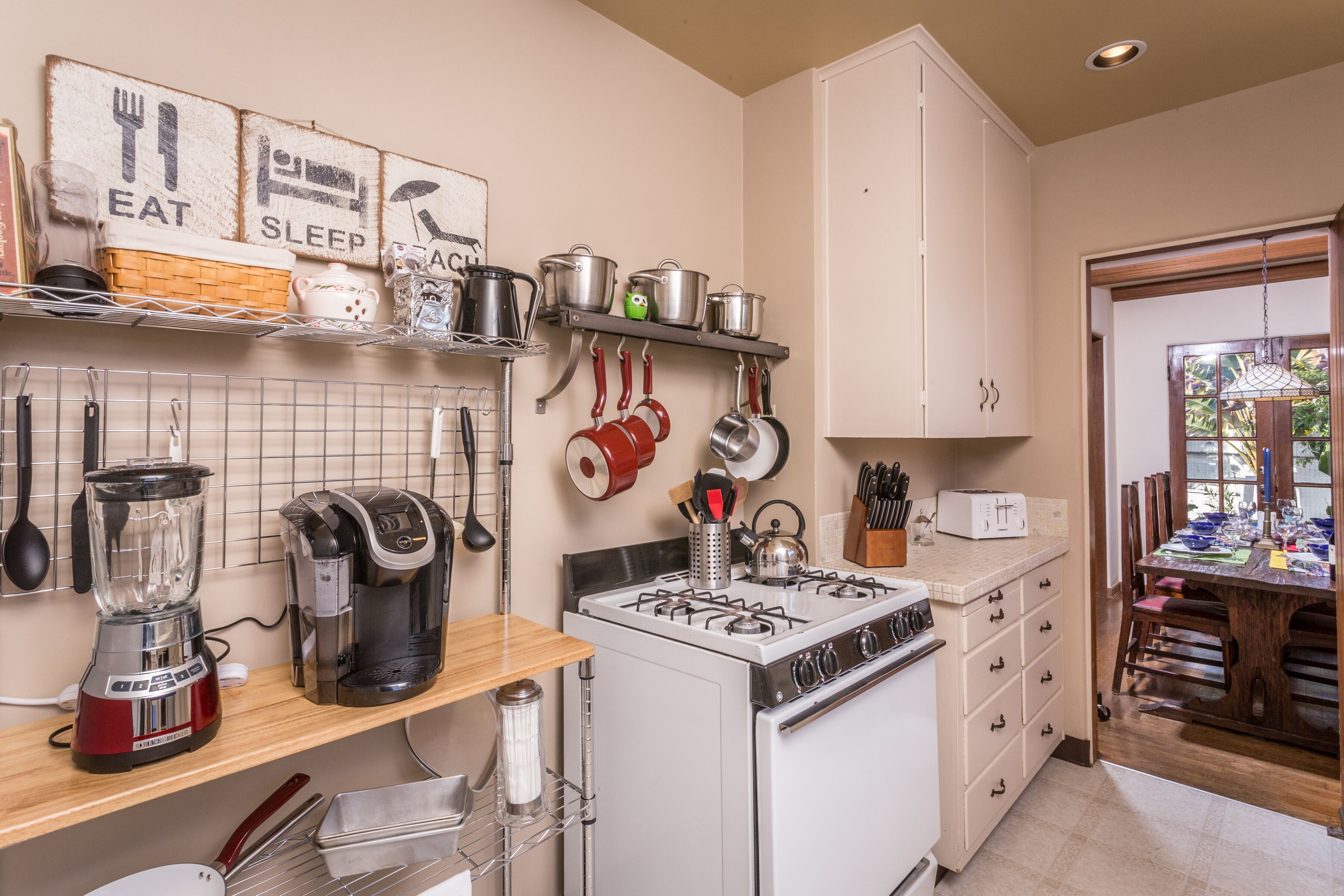 A kitchen with a gas stove, coffee maker, and various utensils. There are cabinets and a countertop with a toaster.