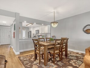 A modern kitchen with white cabinets, a dining area with a wooden table and chairs, and a chandelier.