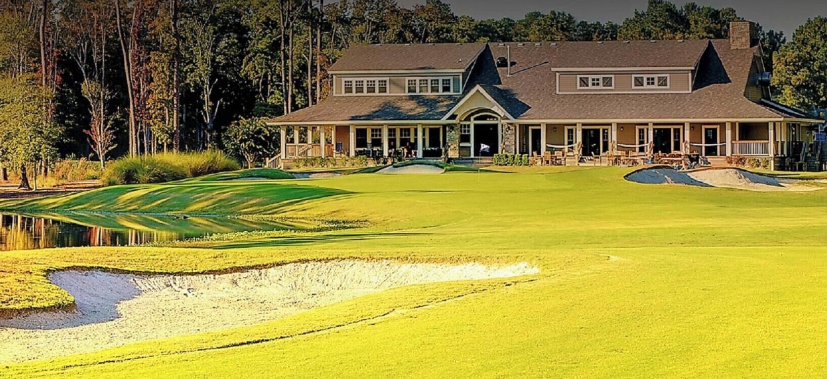 A golf course with a clubhouse and a pond.