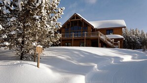 Una cabaña de madera con balcón, rodeada de árboles cubiertos de nieve.