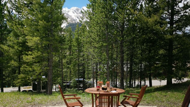 Un jacuzzi con sillas y una mesa de madera, rodeado de árboles y vistas a la montaña.