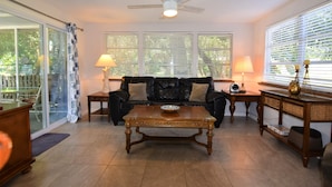 A living room with a black leather sofa, a wooden coffee table, a ceiling fan, and a large window with blinds. - Private Large Pool Getaway Near Siesta Key Gulf Gate Home (Sarasota)