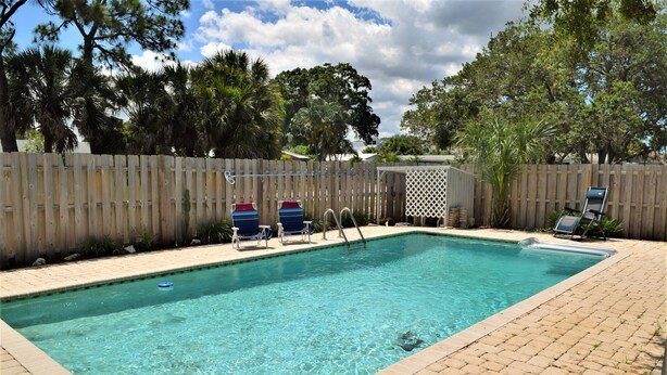 A rectangular swimming pool with clear blue water, surrounded by a wooden fence and a paved deck. - Private Large Pool Getaway Near Siesta Key Gulf Gate Home (Sarasota)