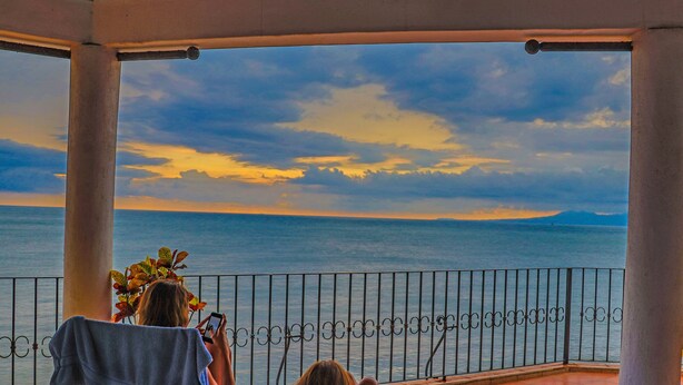 A covered balcony with a view of the sea and sky.