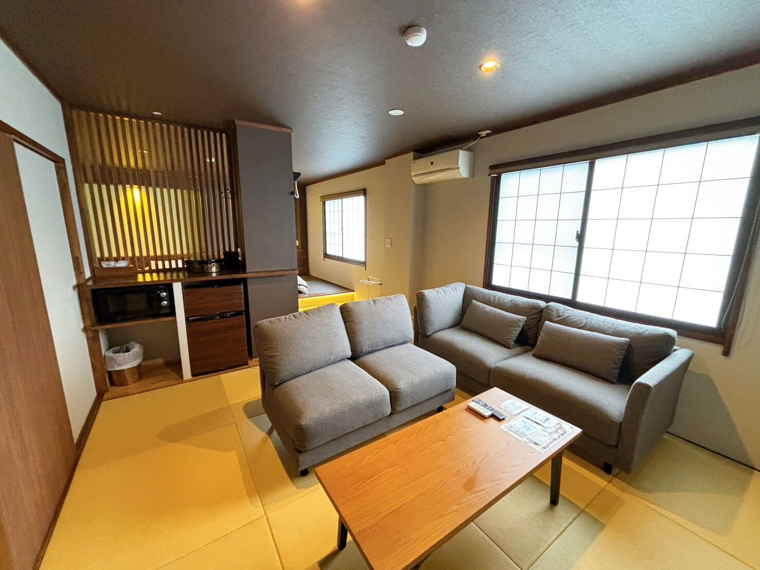 Una sala de estar moderna con sofá, una mesa de centro y una zona de cocina con ventana.