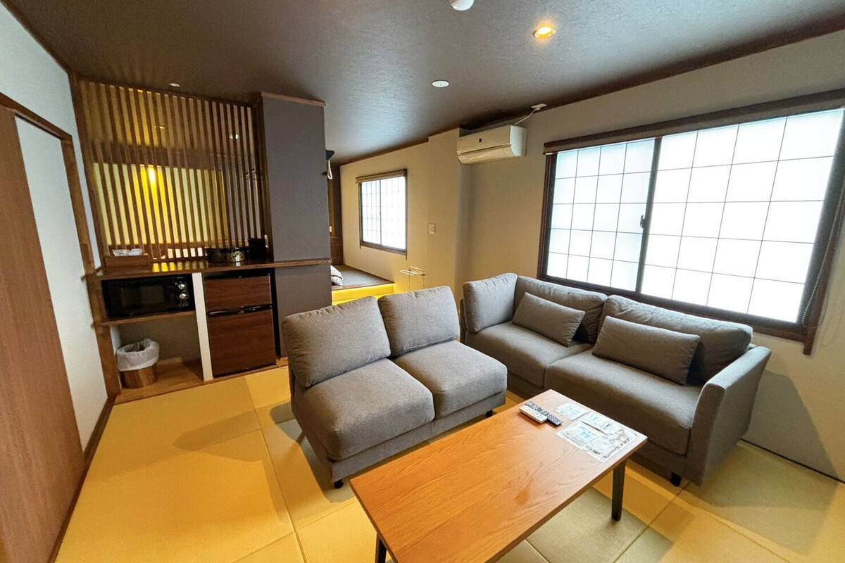 A modern living room with a sofa, a coffee table, and a kitchen area with a window.