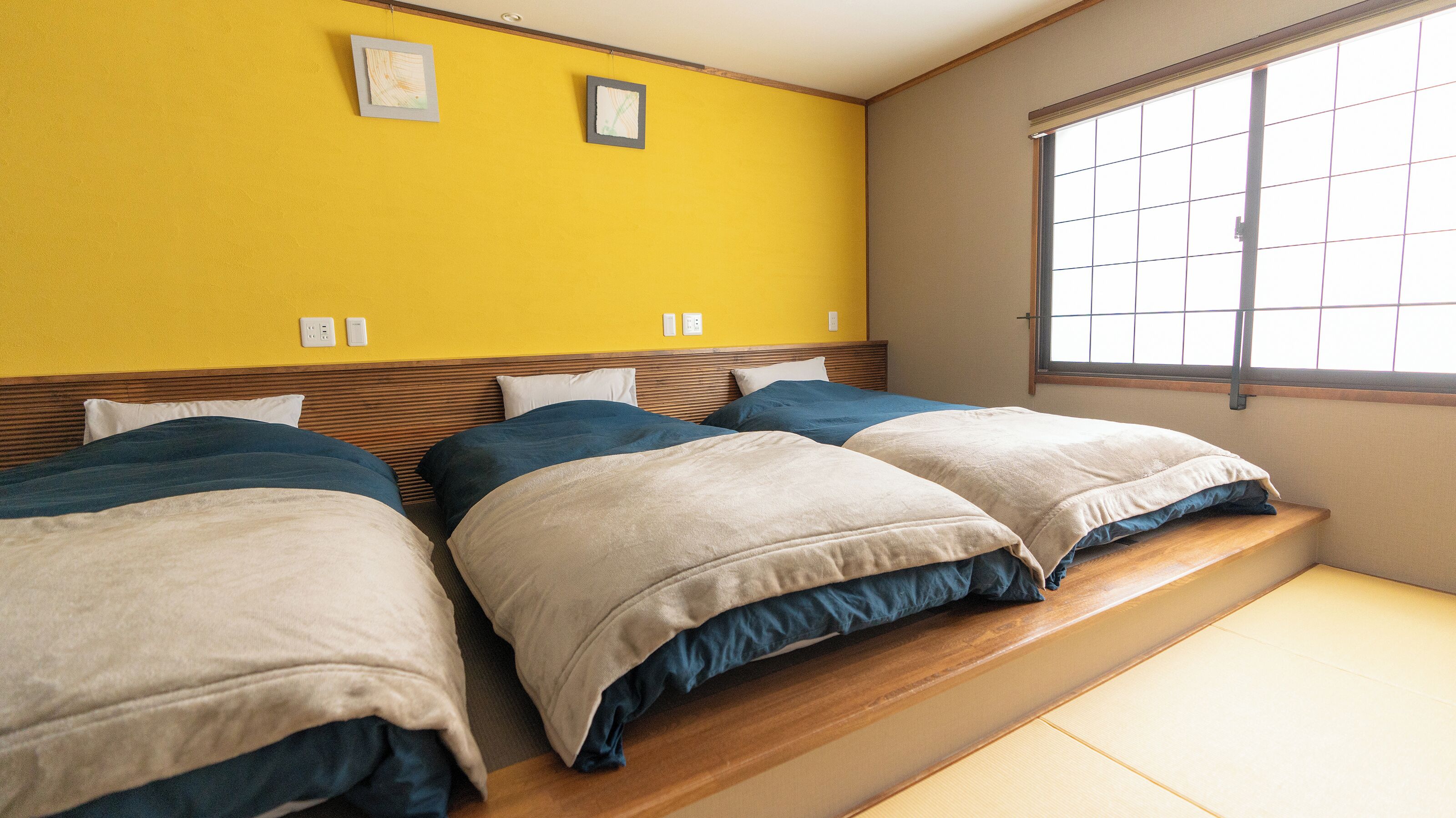 Una habitación de hotel con dos camas, una ventana y una pared amarilla.